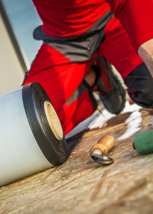 Construction Worker Installing EPDM vinyl on top of BUilding Roof Close Up Photo