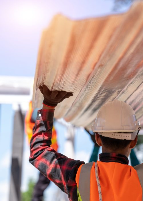 The Roofer technicians work and installing new roof structure on top roof of house,metal roof,fasteners corrugated sheets.