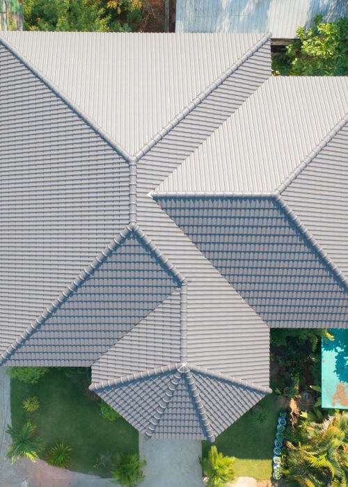 Aerial top view of white double corrugated tiles on roof home or house building. Pattern texture background. Shingle construction. Urban city town.