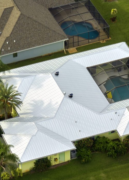 Aerial view of typical contemporary american private house with roof top covered with asphalt shingles and green lawn on yard.
