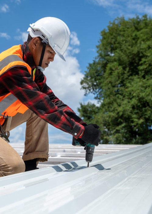 The Roofer technicians work and installing new roof structure on top roof of house,metal roof,fasteners corrugated sheets.