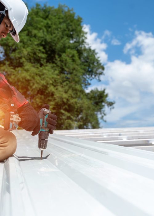 Roofer working at metal profile roof installation,Roofing tools,Electric drill used on new roofs.