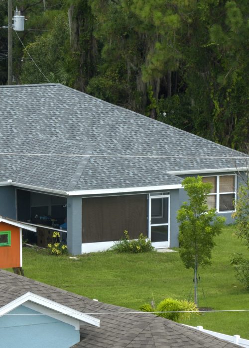 Aerial view of typical contemporary american private house with roof top covered with asphalt shingles and green lawn on yard.