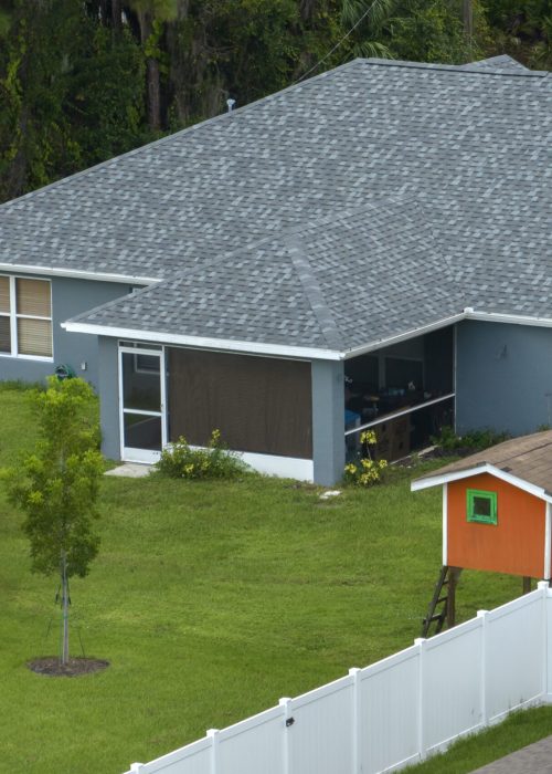 White vinyl picket fence on green lawn surrounding property grounds for backyard protection and privacy.
