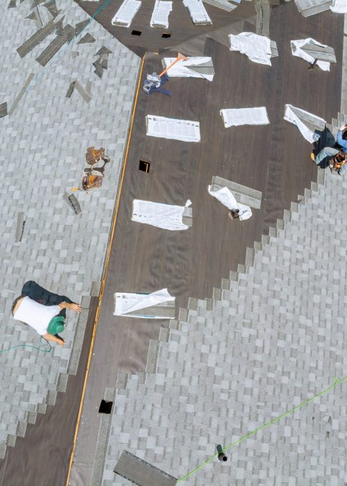 Roofer working on replacement asphalt shingle roof construction