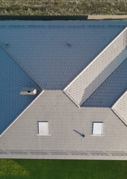 Aerial view of house roof top covered with ceramic shingles. Tiled covering of building under construction.